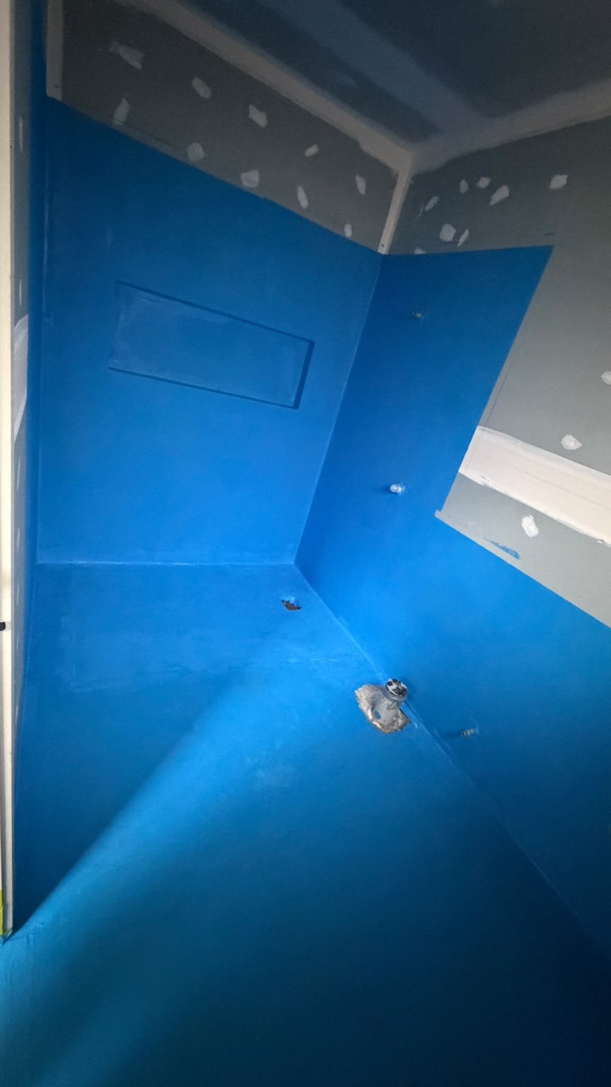 Client bathroom shower waterproofing membrane applied across the walls and floor before tiling